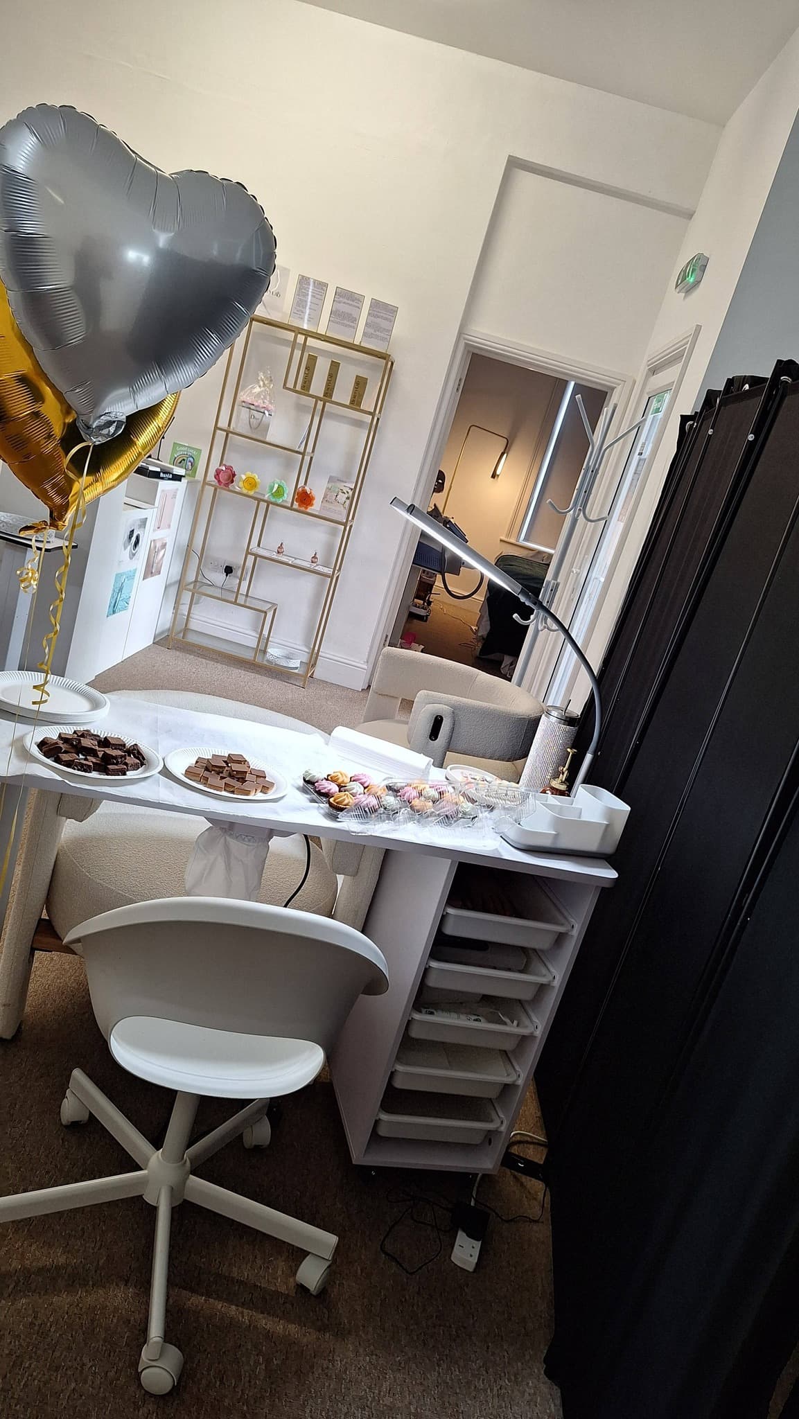 Niki's dedicated nail station with white desk, gold-leg chair and gold ladder shelving in the background.